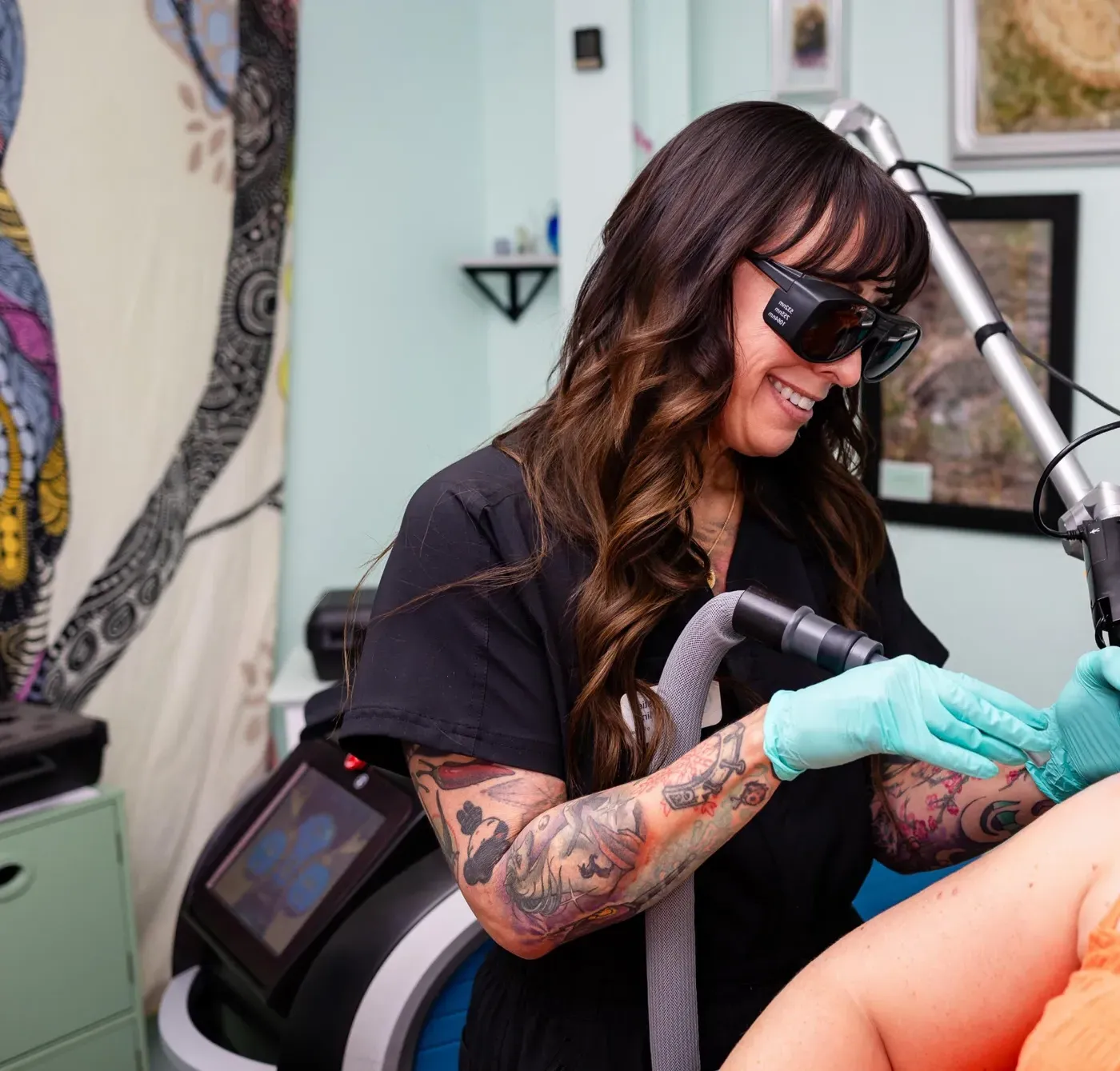 Christie Carlin, owner of Wise Choice Laser Clinic, smiling in protective eyewear while performing a laser treatment